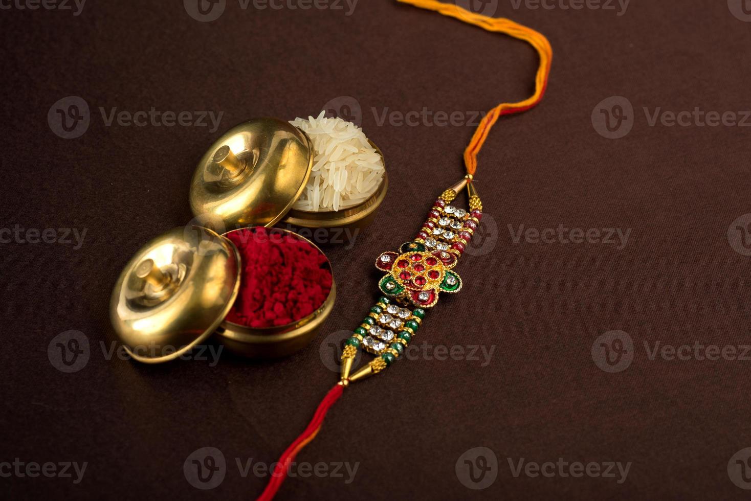 Fondo de raksha bandhan con un elegante rakhi, granos de arroz y kumkum. una pulsera tradicional india que es un símbolo del amor entre hermanos y hermanas. foto