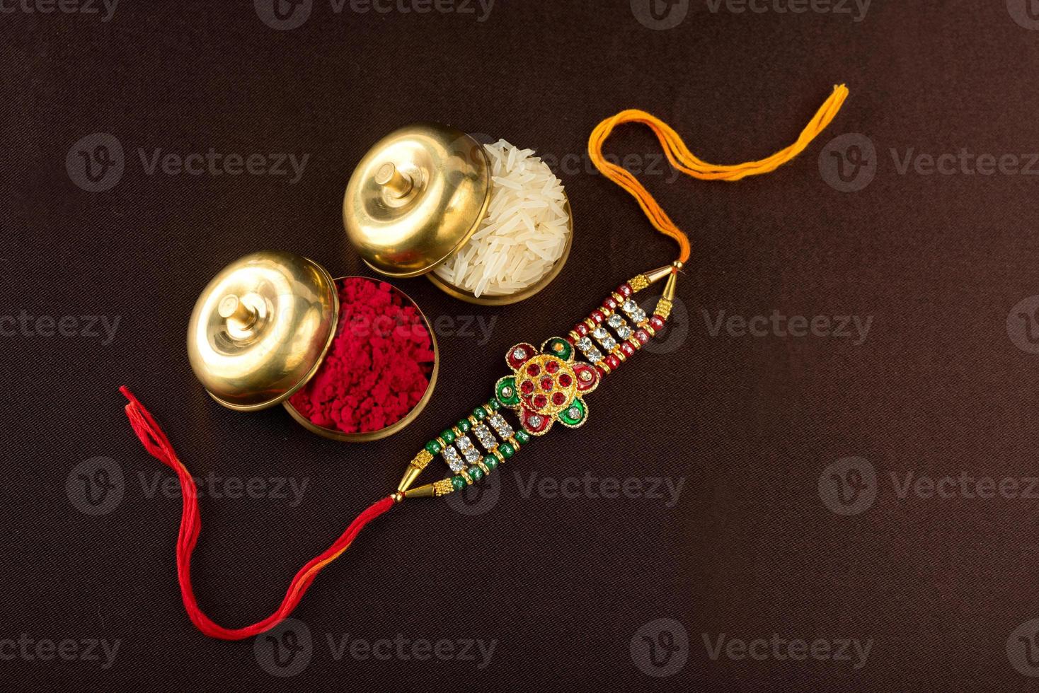 Raksha Bandhan background with an elegant Rakhi, Rice Grains and Kumkum. A traditional Indian wrist band which is a symbol of love between Brothers and Sisters. photo