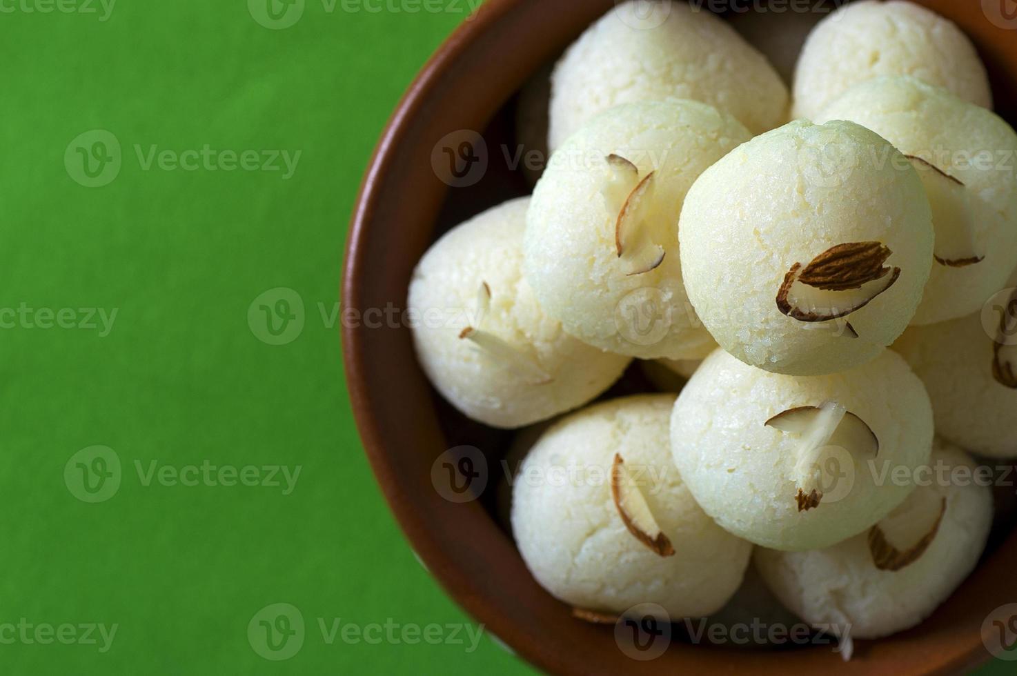 Dulce indio o postre - rasgulla, famoso dulce bengalí en cuenco de arcilla sobre fondo verde foto