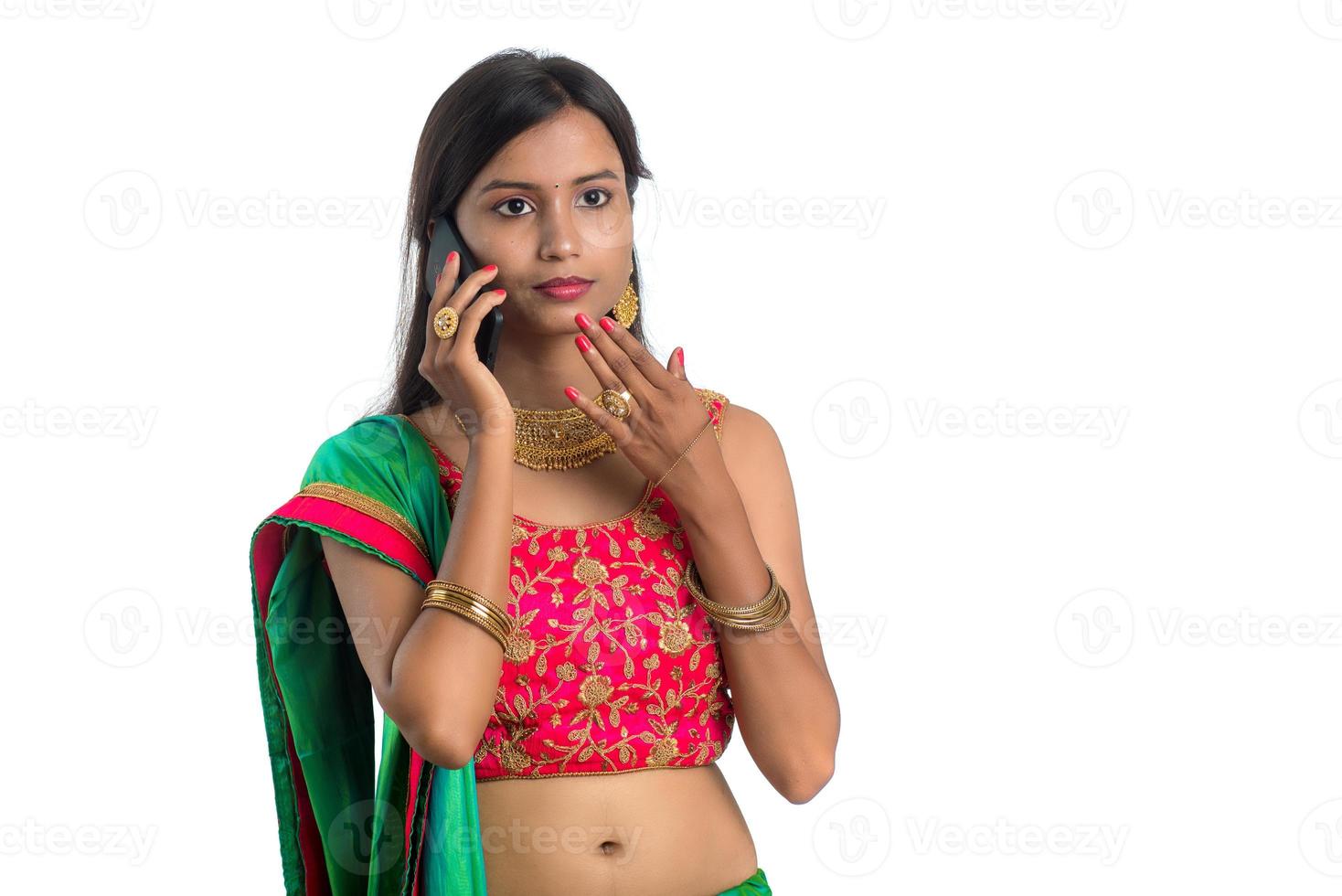 Joven niña tradicional india usando un teléfono móvil o smartphone aislado sobre un fondo blanco. foto