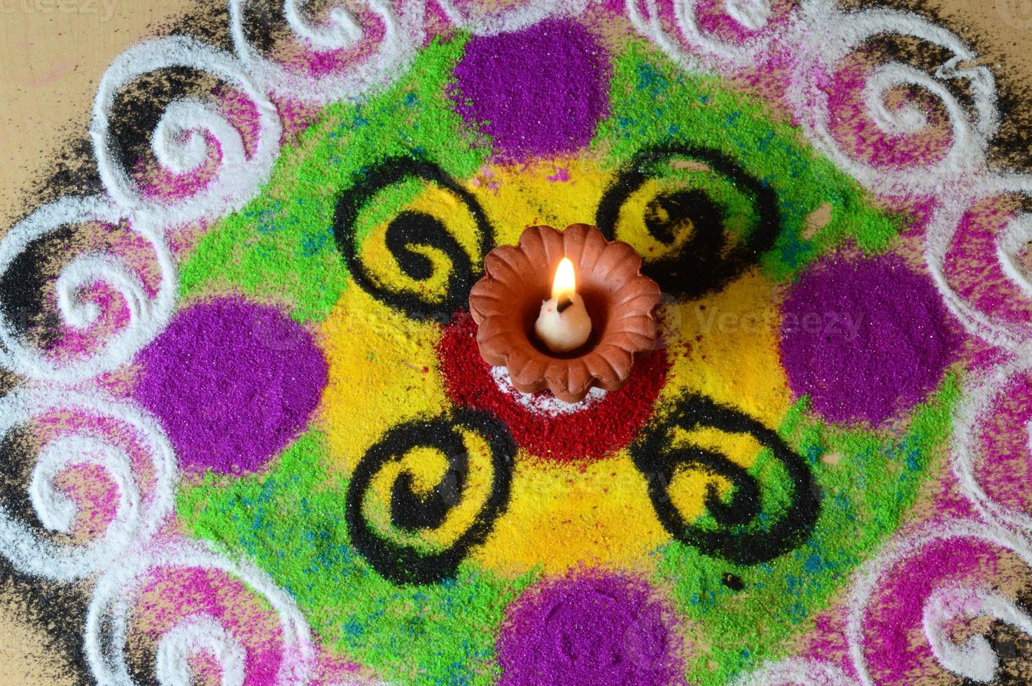 Lámparas de arcilla diya encendidas durante la celebración de Diwali, rangoli en segundo plano. foto