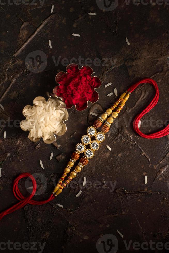 Raksha Bandhan background with an elegant Rakhi, Rice Grains and Kumkum. A traditional Indian wrist band which is a symbol of love between Brothers and Sisters. photo