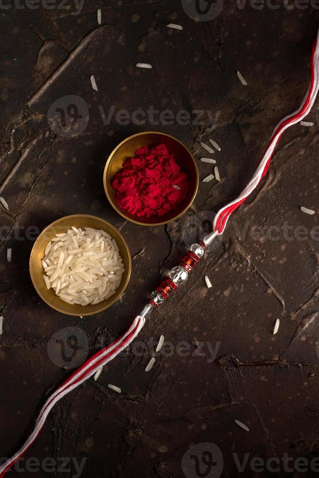 Raksha Bandhan background with an elegant Rakhi, Rice Grains and Kumkum. A traditional Indian wrist band which is a symbol of love between Brothers and Sisters. photo