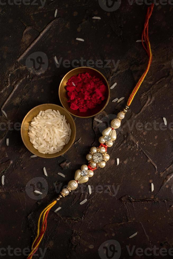 Raksha Bandhan background with an elegant Rakhi, Rice Grains and Kumkum. A traditional Indian wrist band which is a symbol of love between Brothers and Sisters. photo
