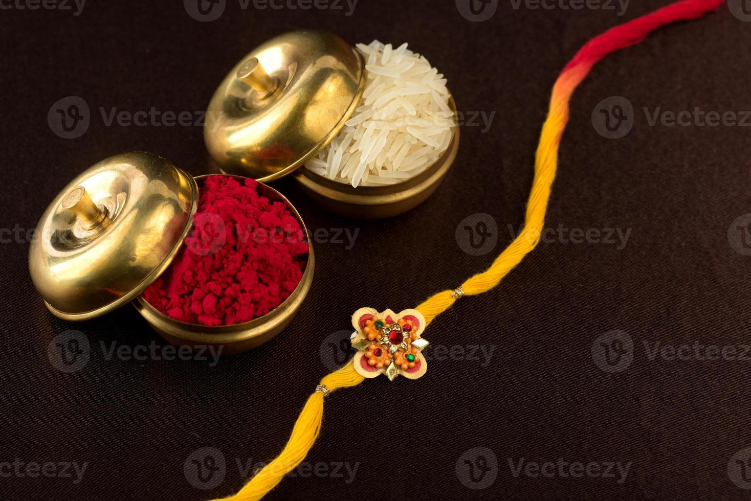 Raksha Bandhan background with an elegant Rakhi, Rice Grains and Kumkum. A traditional Indian wrist band which is a symbol of love between Brothers and Sisters. photo