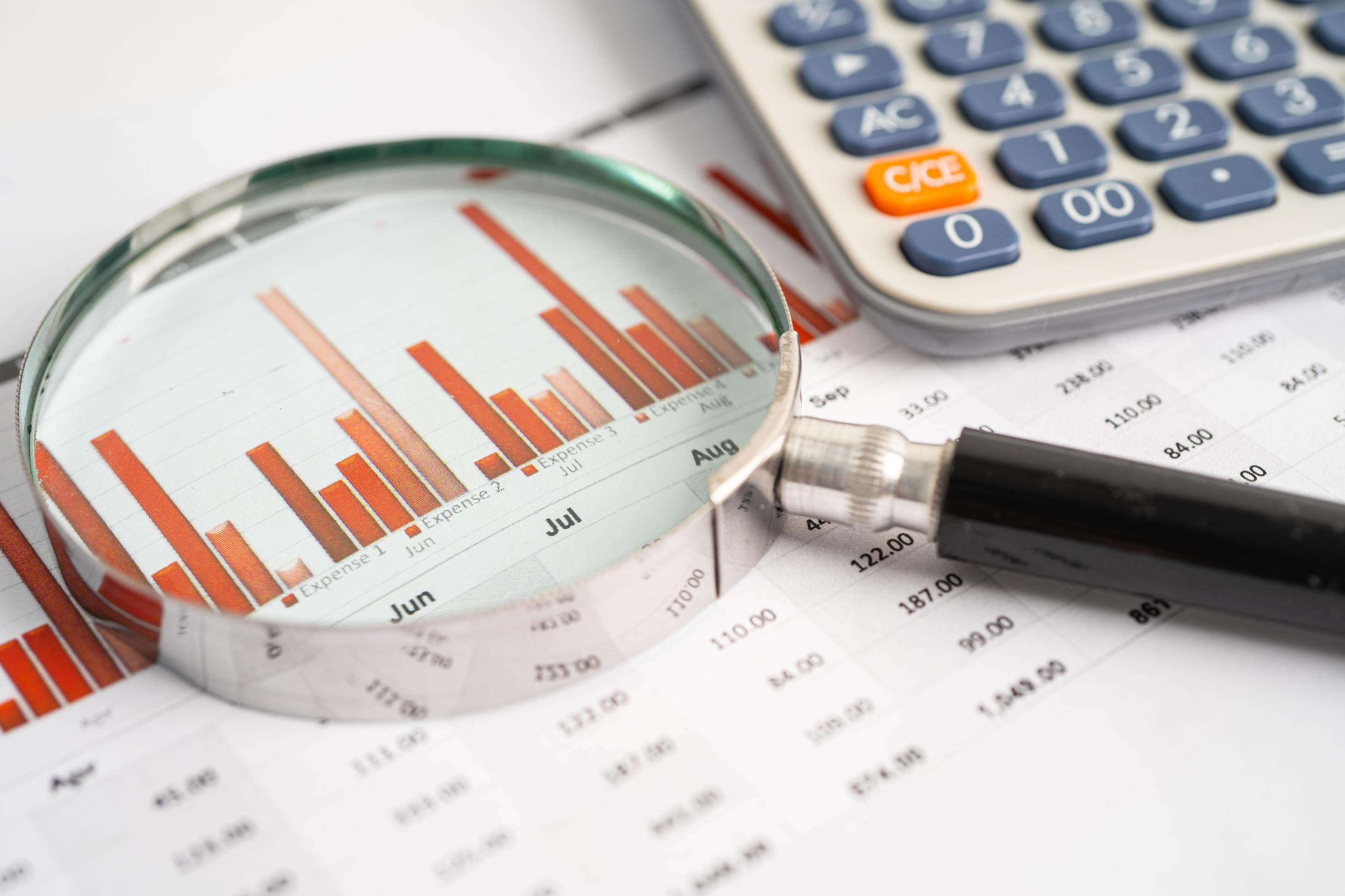 Magnifying glass and calculator on charts graphs paper. Financial ...