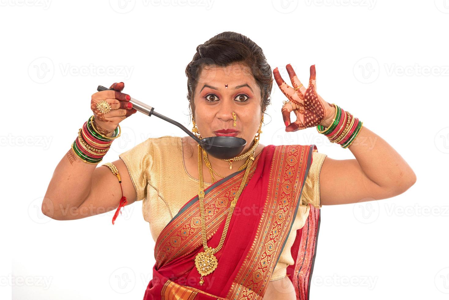 Young Traditional Indian Girl holding kitchen utensil on white background photo