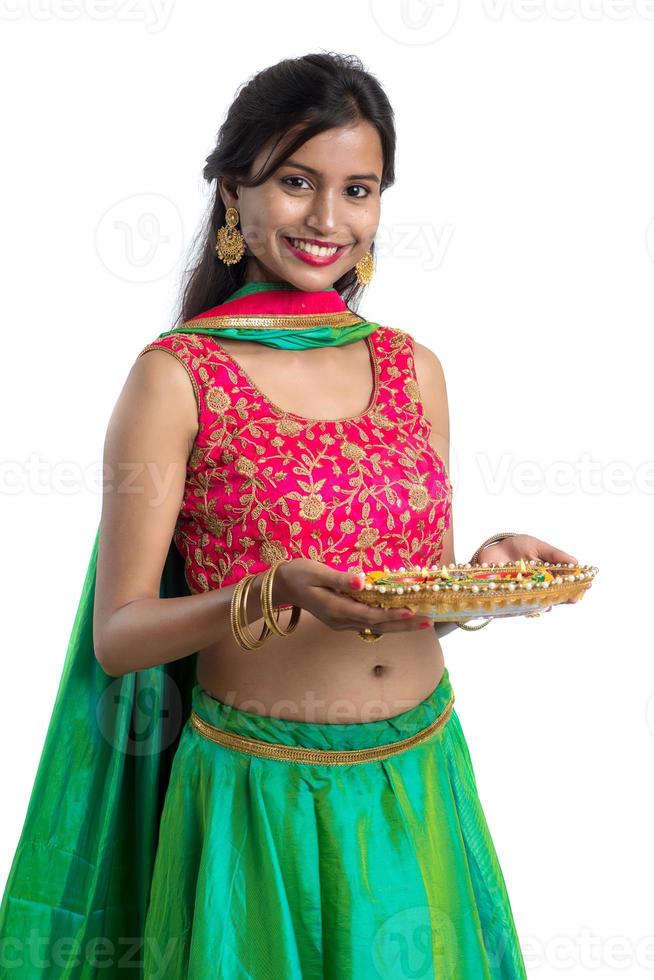 Portrait of a Indian Traditional Girl holding Diya, Girl Celebrating Diwali or Deepavali with holding oil lamp during festival of light on white background photo