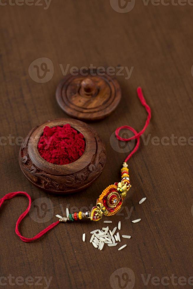 Indian festival Raksha Bandhan background with an elegant Rakhi, Rice Grains and Kumkum. A traditional Indian wrist band which is a symbol of love between Brothers and Sisters. photo