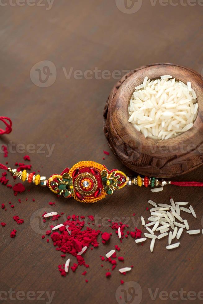 Indian festival Raksha Bandhan background with an elegant Rakhi, Rice Grains and Kumkum. A traditional Indian wrist band which is a symbol of love between Brothers and Sisters. photo