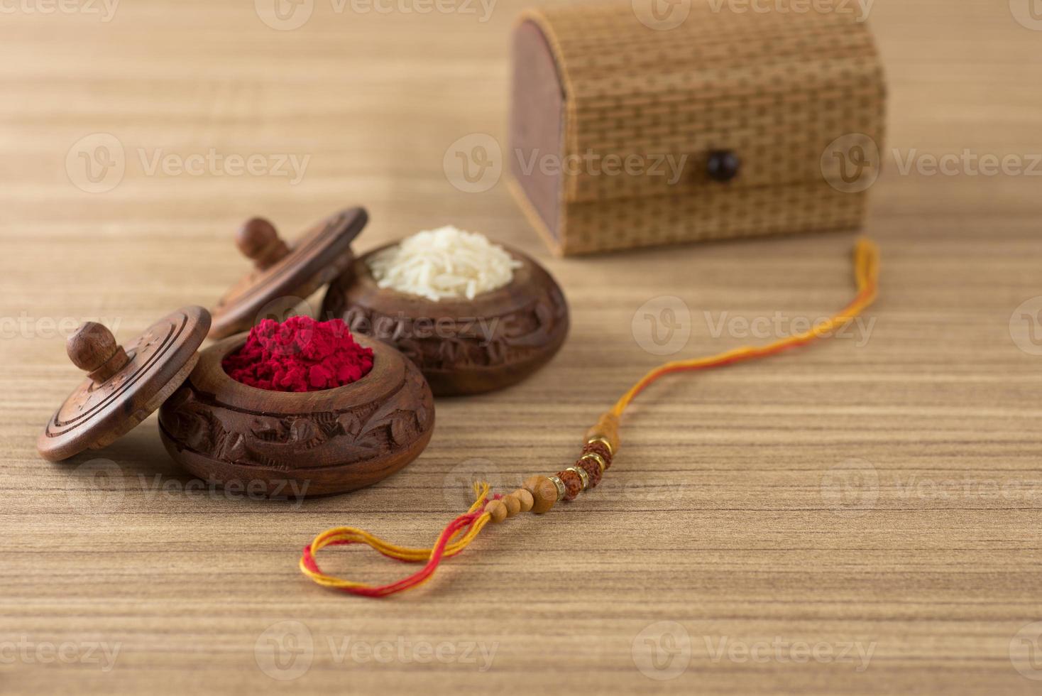 Indian festival Raksha Bandhan background with an elegant Rakhi, Rice Grains and Kumkum. A traditional Indian wrist band which is a symbol of love between Brothers and Sisters. photo
