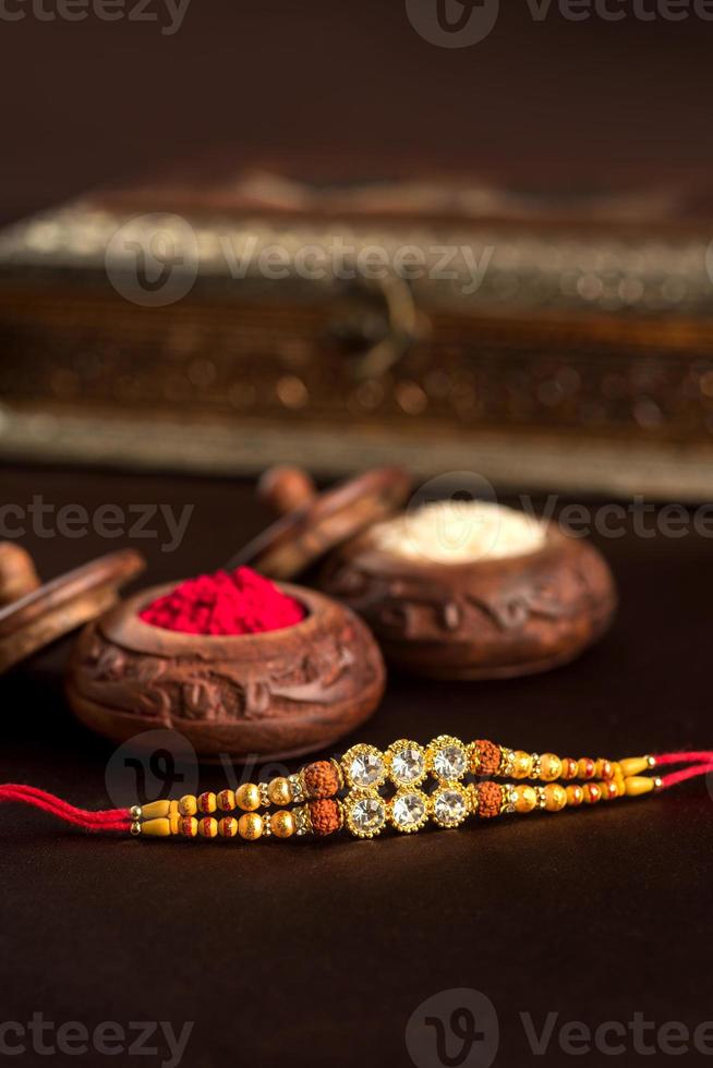 Indian festival Raksha Bandhan background with an elegant Rakhi, Rice Grains and Kumkum. A traditional Indian wrist band which is a symbol of love between Brothers and Sisters. photo
