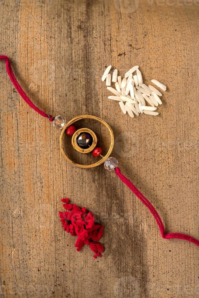 Indian festival Raksha Bandhan background with an elegant Rakhi, Rice Grains and Kumkum. A traditional Indian wrist band which is a symbol of love between Brothers and Sisters. photo