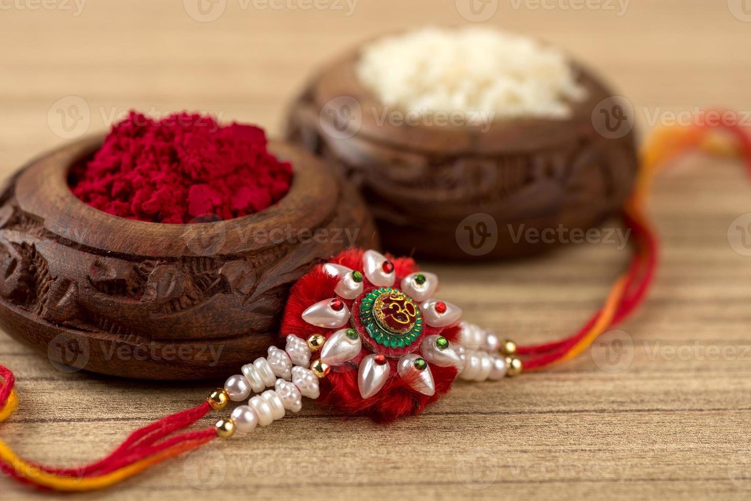 Indian festival Raksha Bandhan background with an elegant Rakhi, Rice Grains and Kumkum. A traditional Indian wrist band which is a symbol of love between Brothers and Sisters. photo