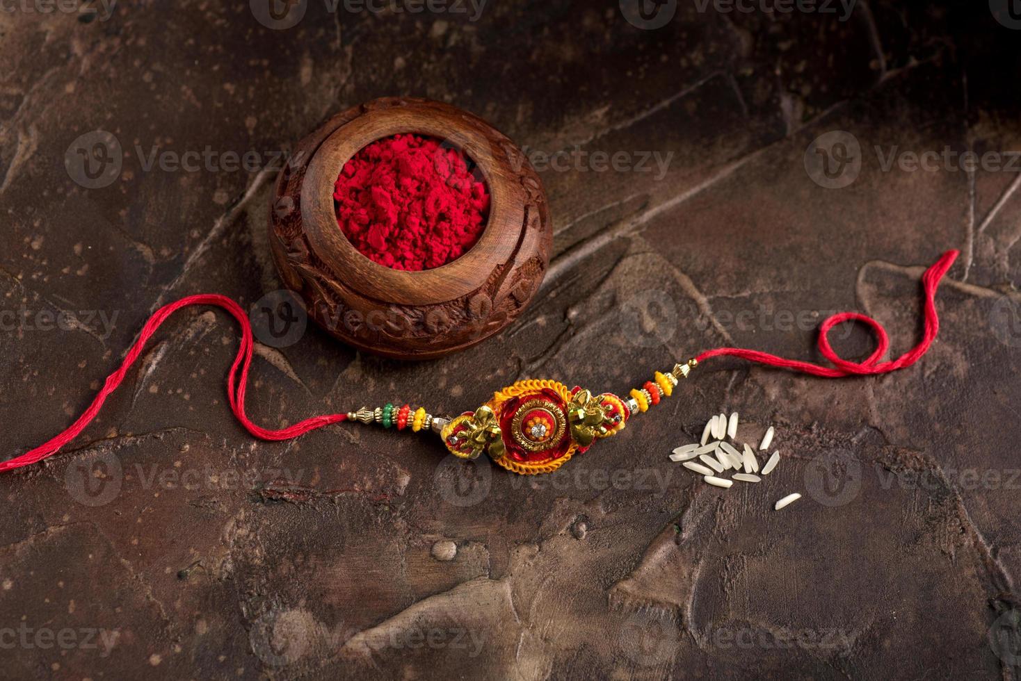 Raksha Bandhan background with an elegant Rakhi, Rice Grains and Kumkum. A traditional Indian wrist band which is a symbol of love between Brothers and Sisters. photo