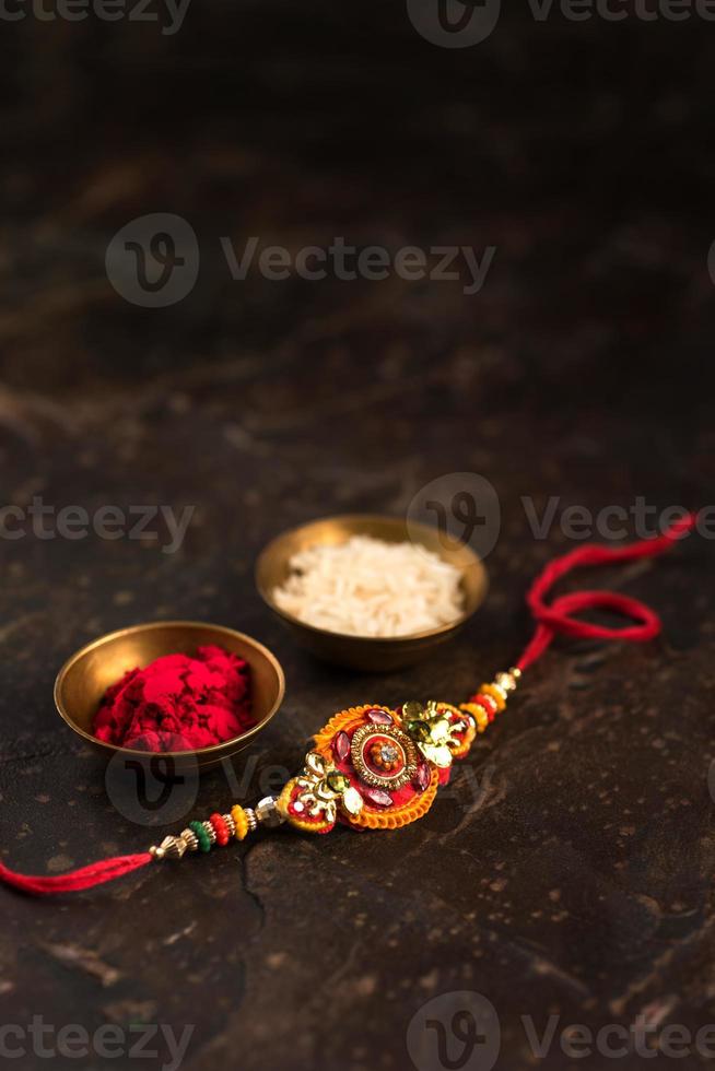 Fondo de raksha bandhan con un elegante rakhi, granos de arroz y kumkum. una pulsera tradicional india que es un símbolo del amor entre hermanos y hermanas. foto