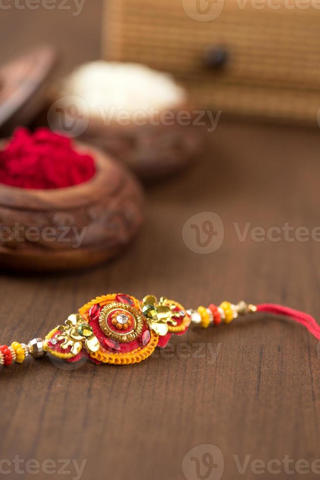 Indian festival Raksha Bandhan background with an elegant Rakhi, Rice Grains and Kumkum. A traditional Indian wrist band which is a symbol of love between Brothers and Sisters. photo