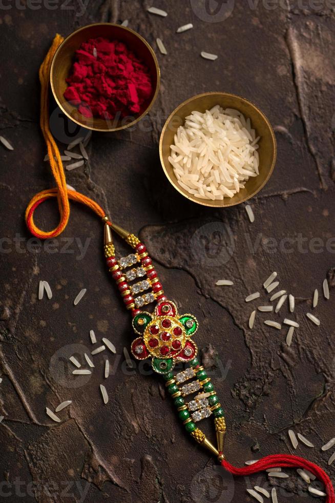 Raksha Bandhan background with an elegant Rakhi, Rice Grains and Kumkum. A traditional Indian wrist band which is a symbol of love between Brothers and Sisters. photo