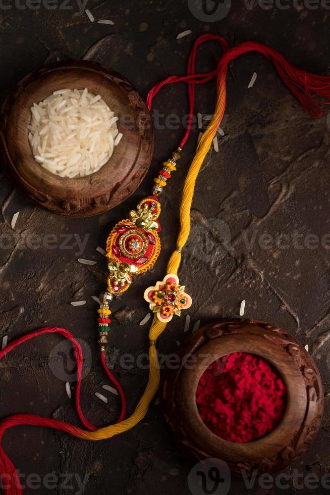 Raksha Bandhan background with an elegant Rakhi, Rice Grains and Kumkum. A traditional Indian wrist band which is a symbol of love between Brothers and Sisters. photo