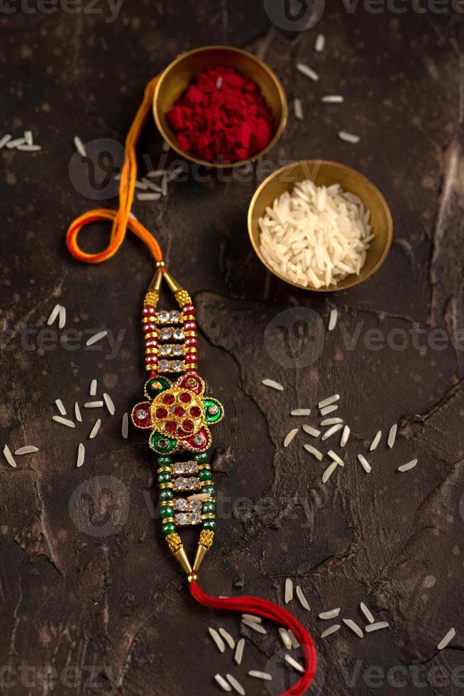 Raksha Bandhan background with an elegant Rakhi, Rice Grains and Kumkum. A traditional Indian wrist band which is a symbol of love between Brothers and Sisters. photo