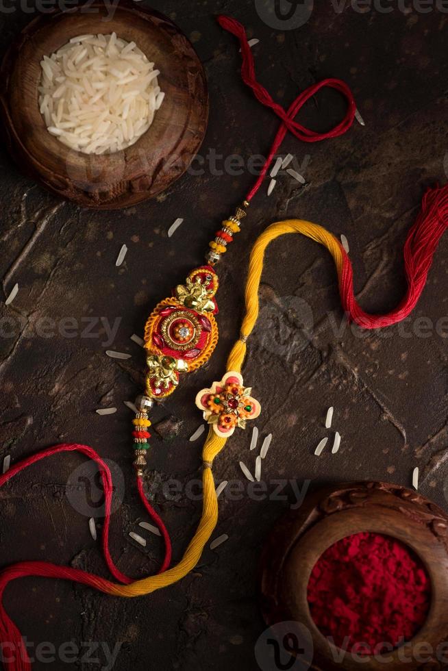 Raksha Bandhan background with an elegant Rakhi, Rice Grains and Kumkum. A traditional Indian wrist band which is a symbol of love between Brothers and Sisters. photo