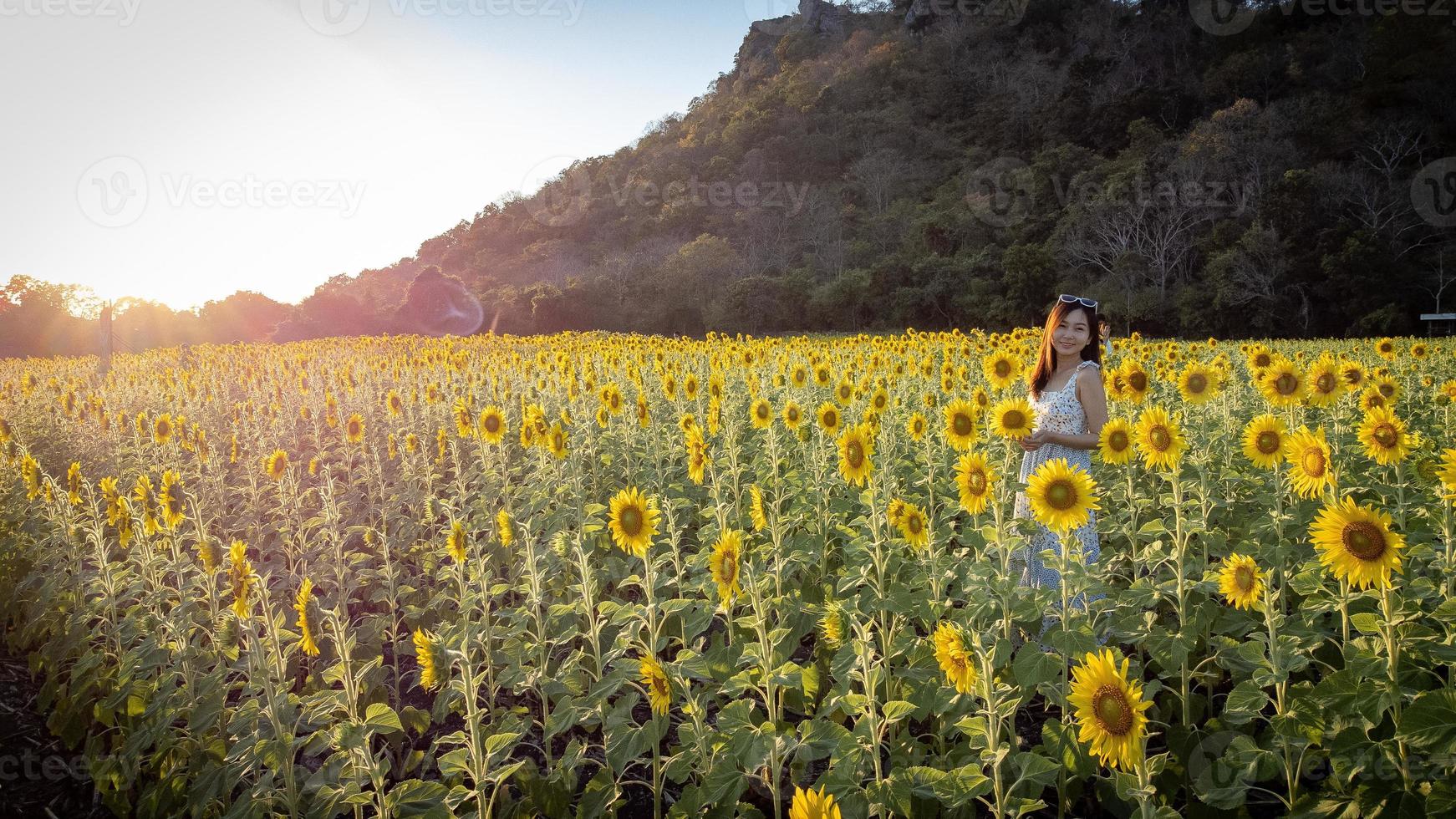 Happy joyful asian girl with sunflower enjoying nature and smile on summer in sunflower field. photo