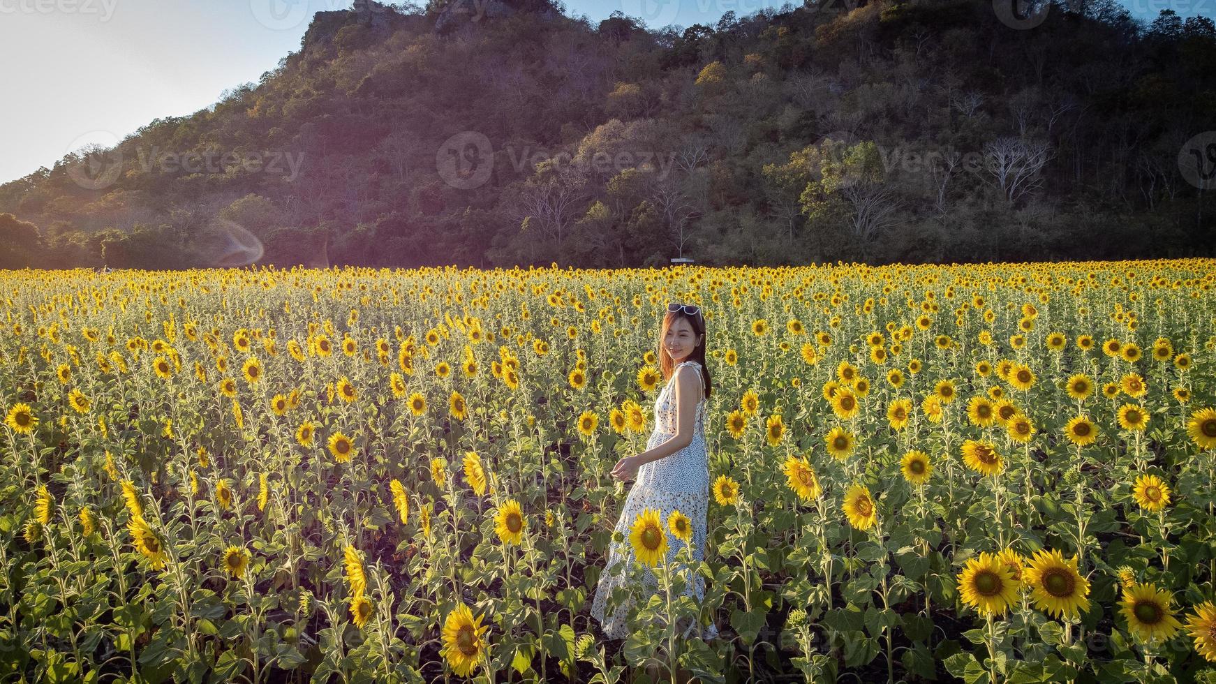 Happy joyful asian girl with sunflower enjoying nature and smile on summer in sunflower field. photo