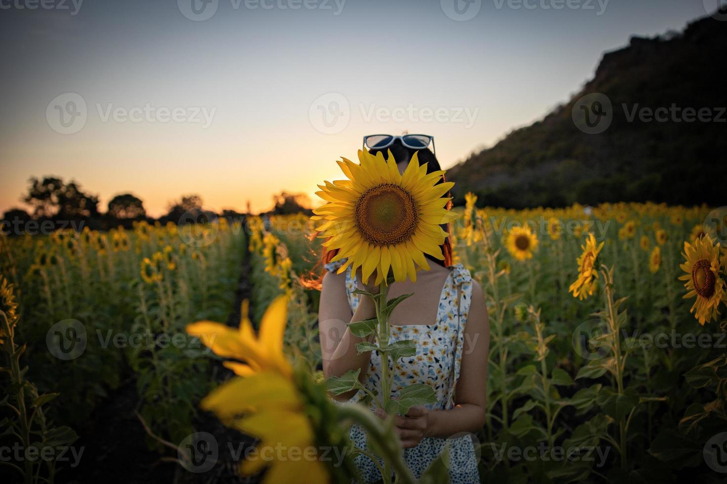 Happy joyful asian girl with sunflower enjoying nature and smile on summer in sunflower field. photo