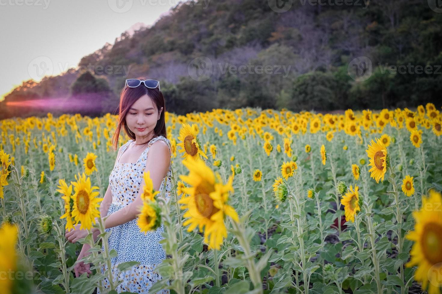 Happy joyful asian girl with sunflower enjoying nature and smile on summer in sunflower field. photo