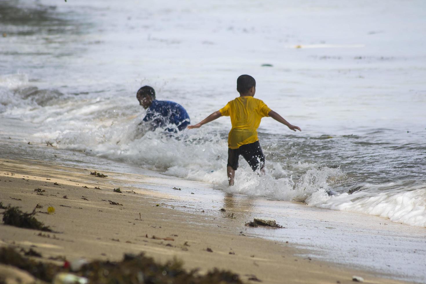 Sorong, Papua Occidental, Indonesia, 12 de diciembre de 2021. Niños jugando contra las olas en la playa foto