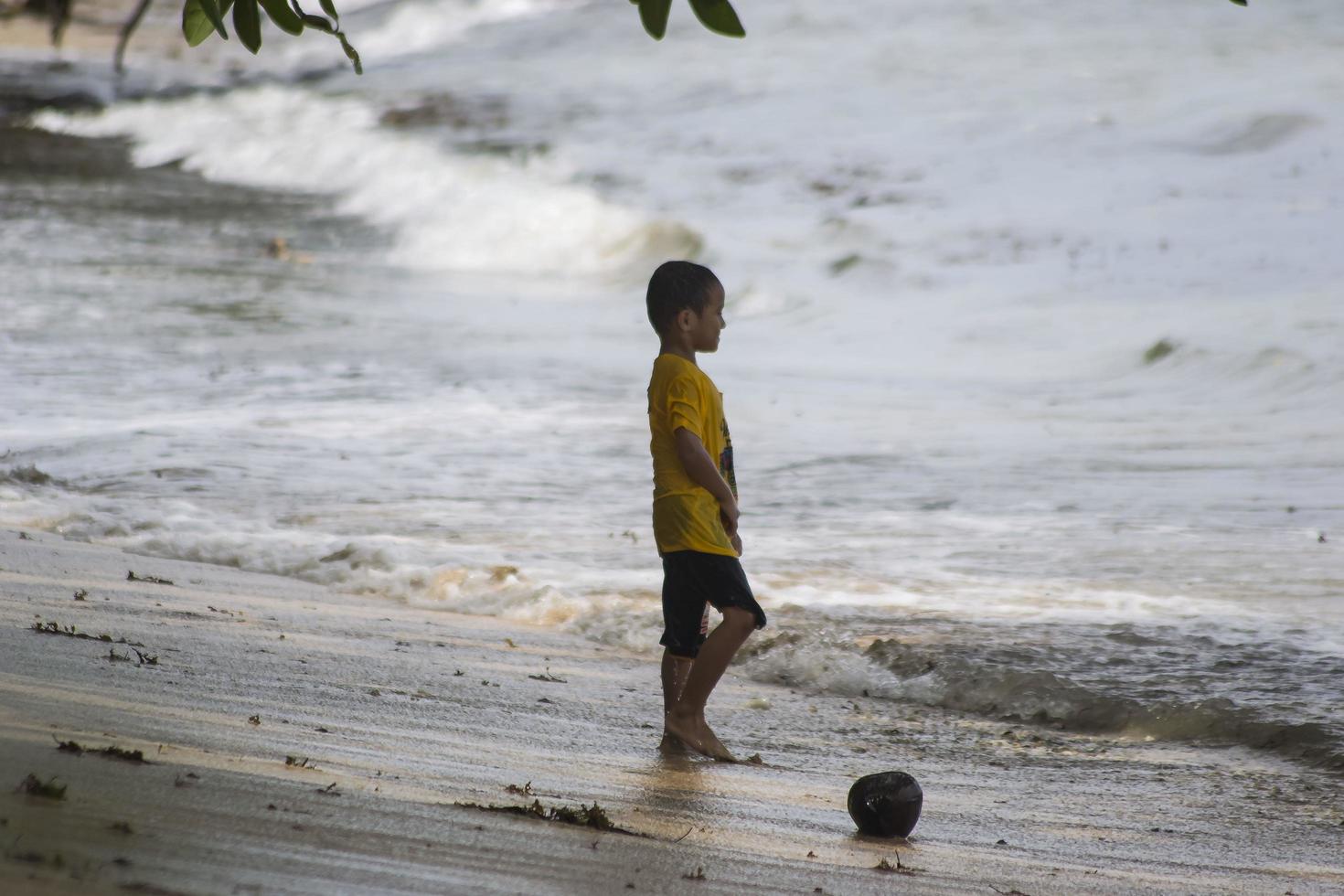 Sorong, West Papua, Indonesia, December 12th 2021. Boys playing against the waves on the beach photo