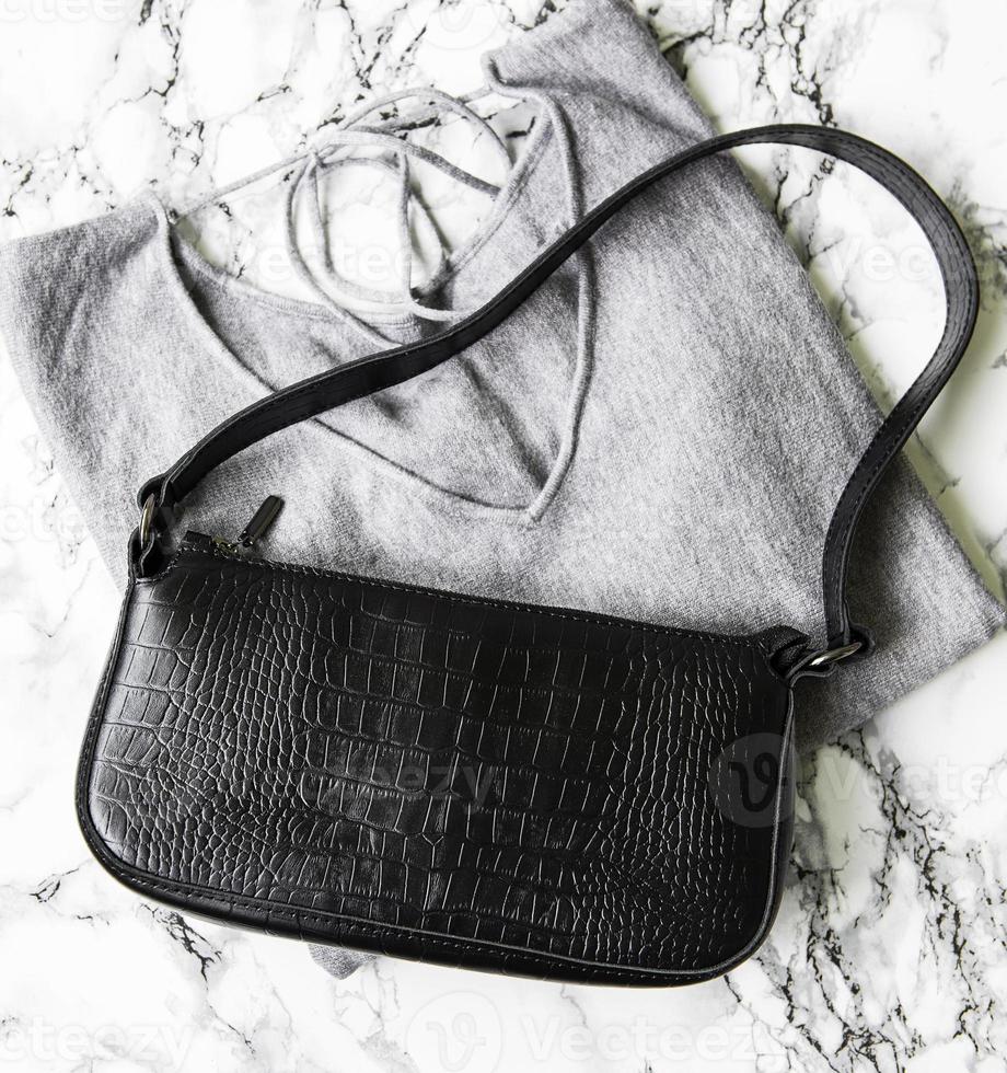 Small black leather bag and gray women's sweater photo