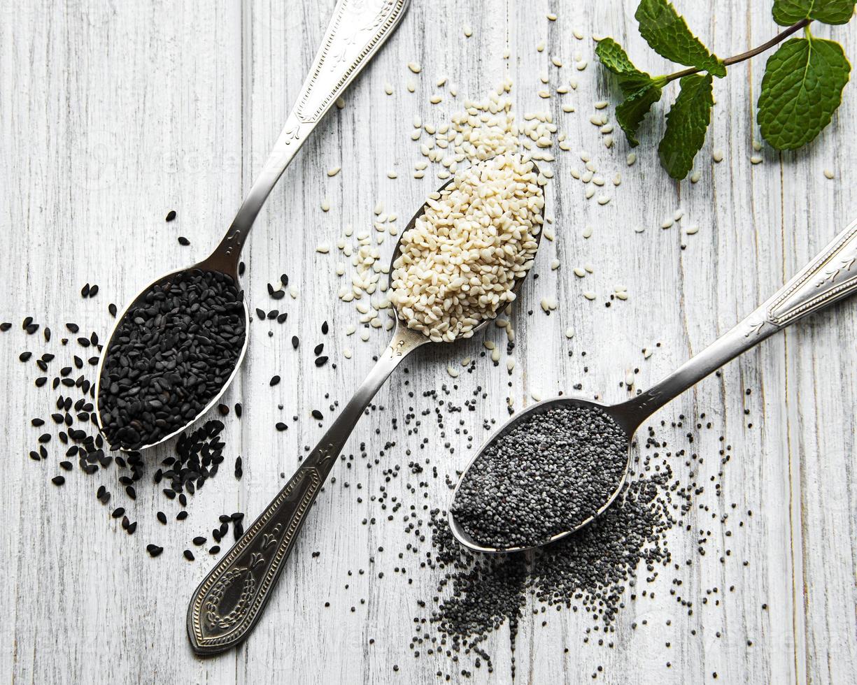 Black and white sesame seeds and poppy seeds in a spoons photo