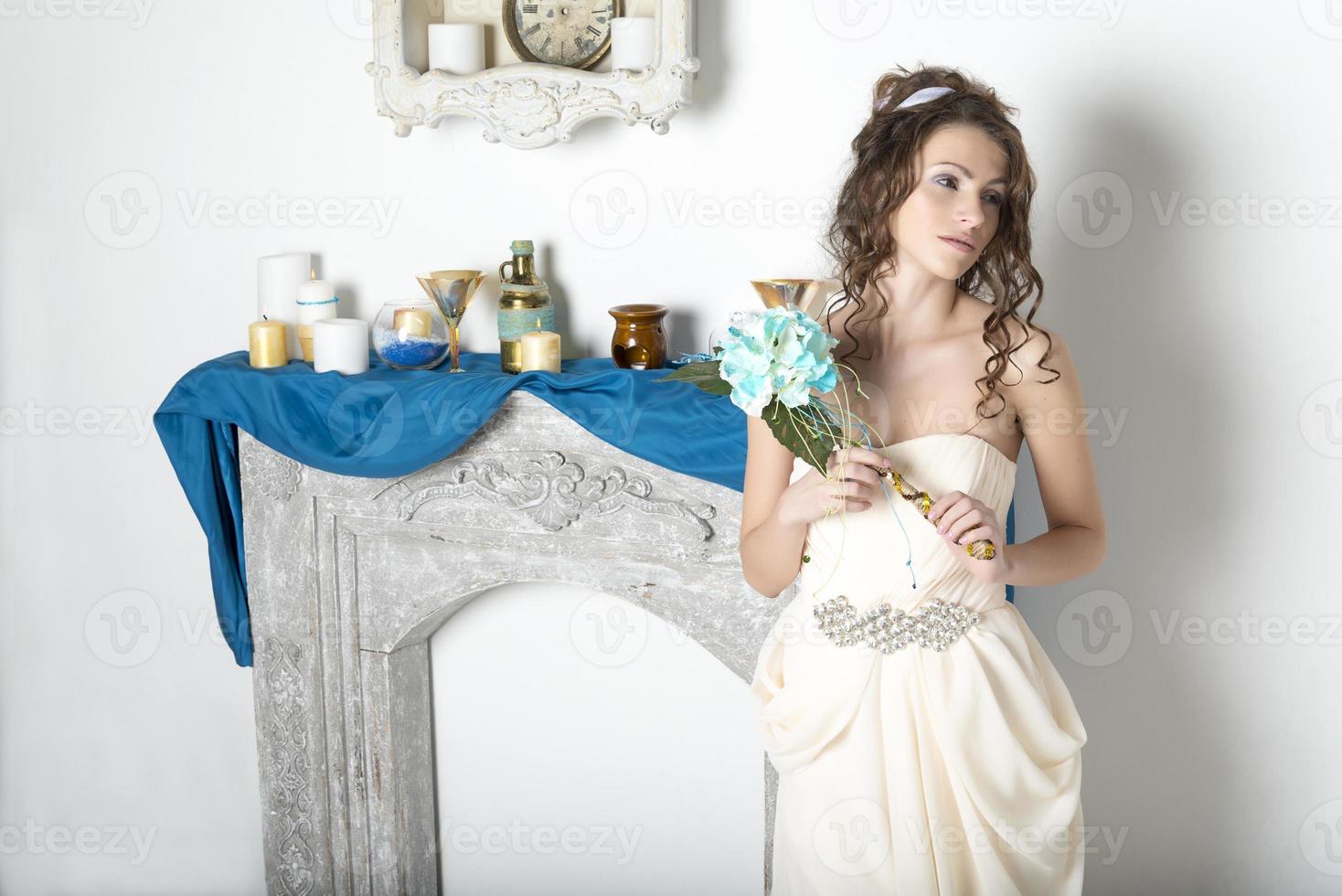 Girl in white near the decorative fireplace. photo