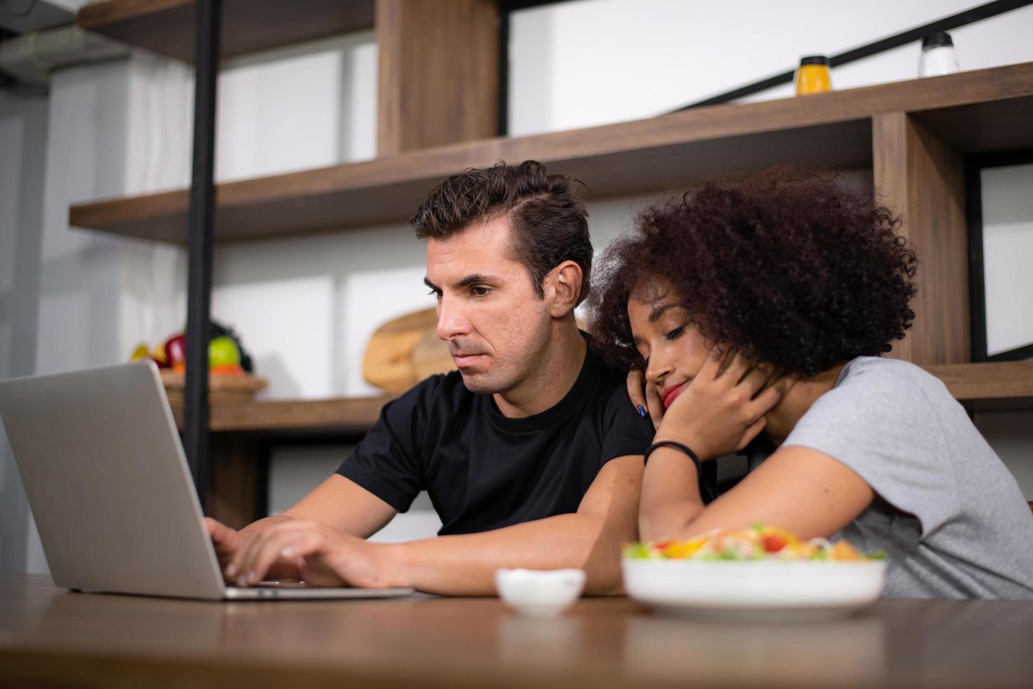 Young couple is feeding while cooking salad photo