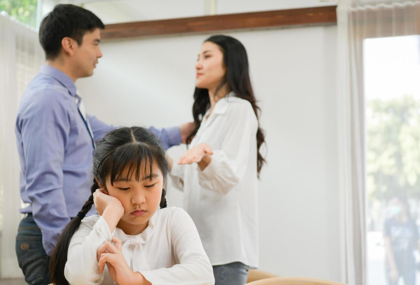 una niña triste que aguantaba escuchar a sus padres discutir en casa. foto