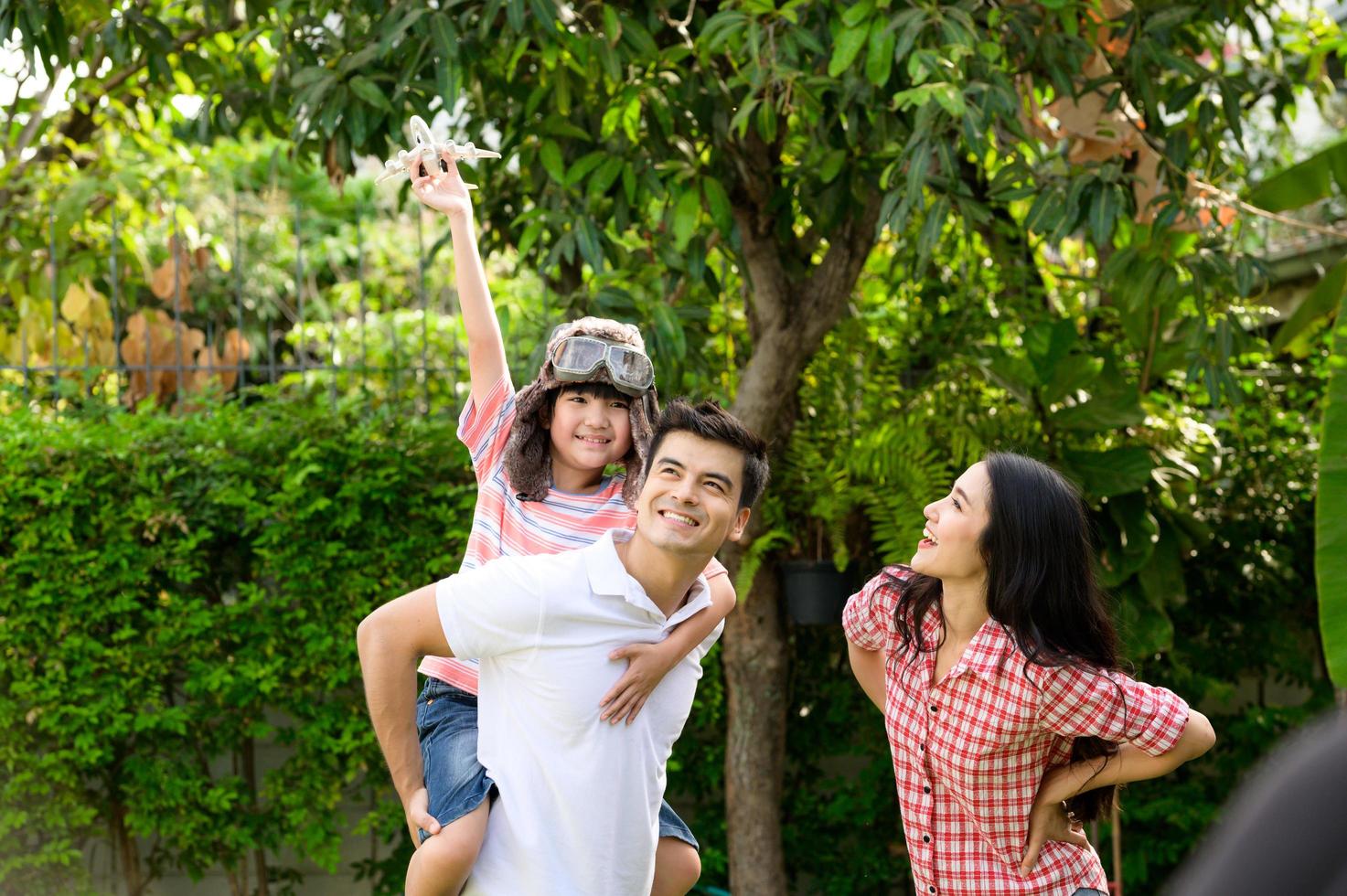 A happy young family spends time playing together in the garden at the front of house the vacation. photo