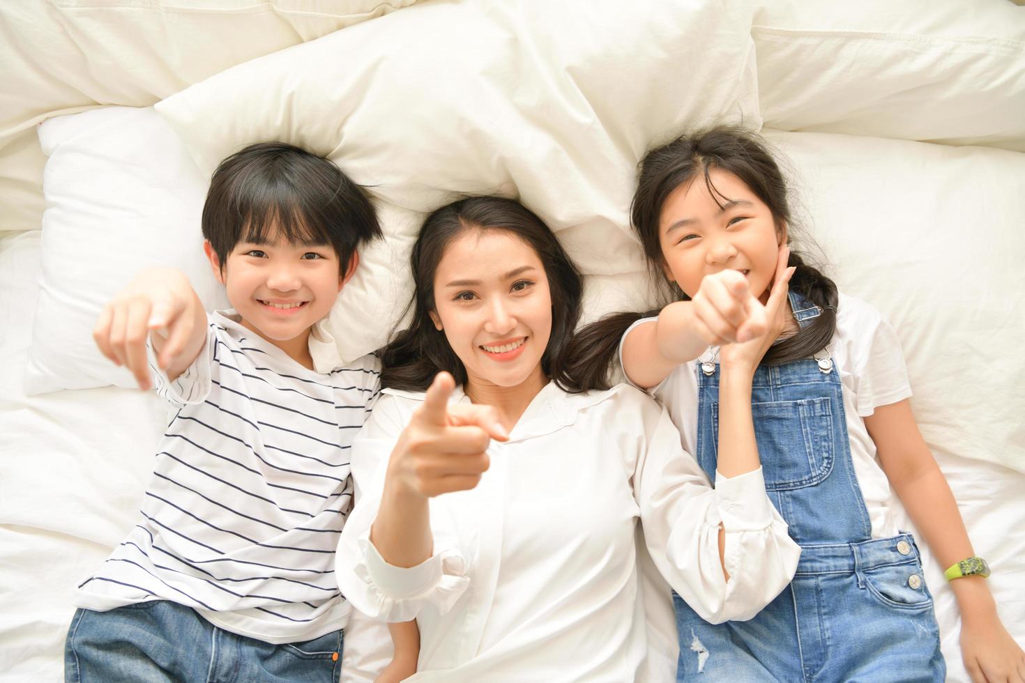 Momentos felices familiares cuando los niños se despiertan por la mañana. Diviértete con mamá antes de desayunar. foto