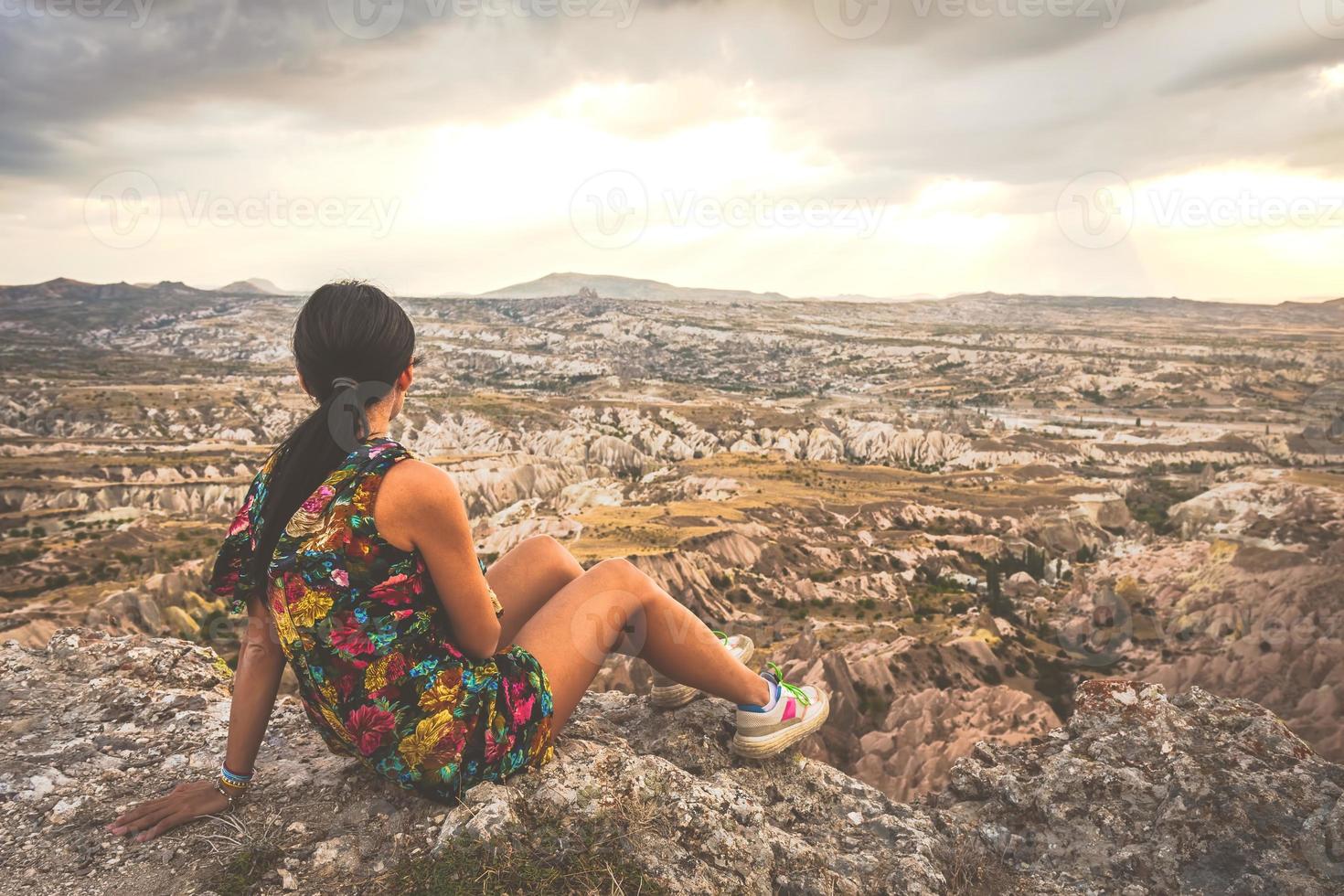 Female woman tourist in dress looking over the dramatic red valley with dramatic sky background. Solo exploration in Turkey. Cinematic Travel photo