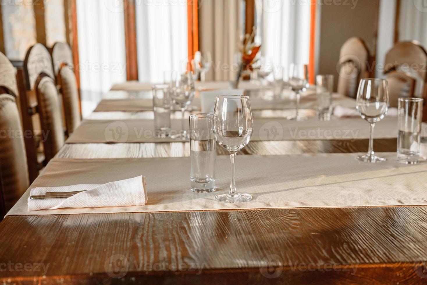 Glasses, flower fork, knife served for dinner in restaurant with cozy interior photo