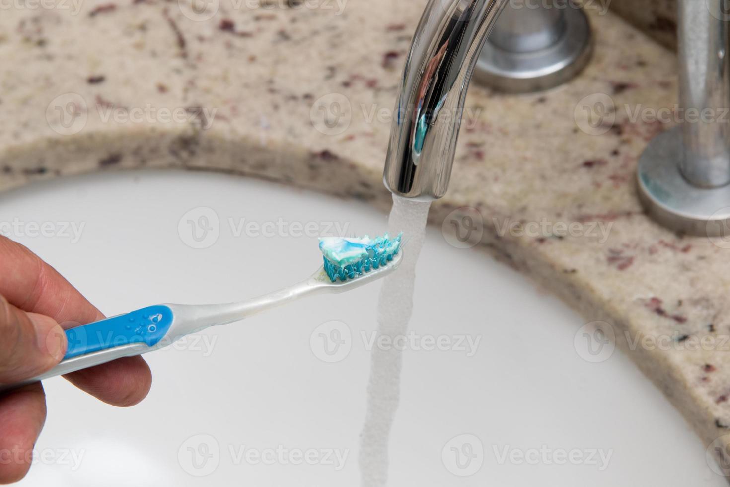 Hombre sujetando su cepillo de dientes desgastado bajo el agua foto