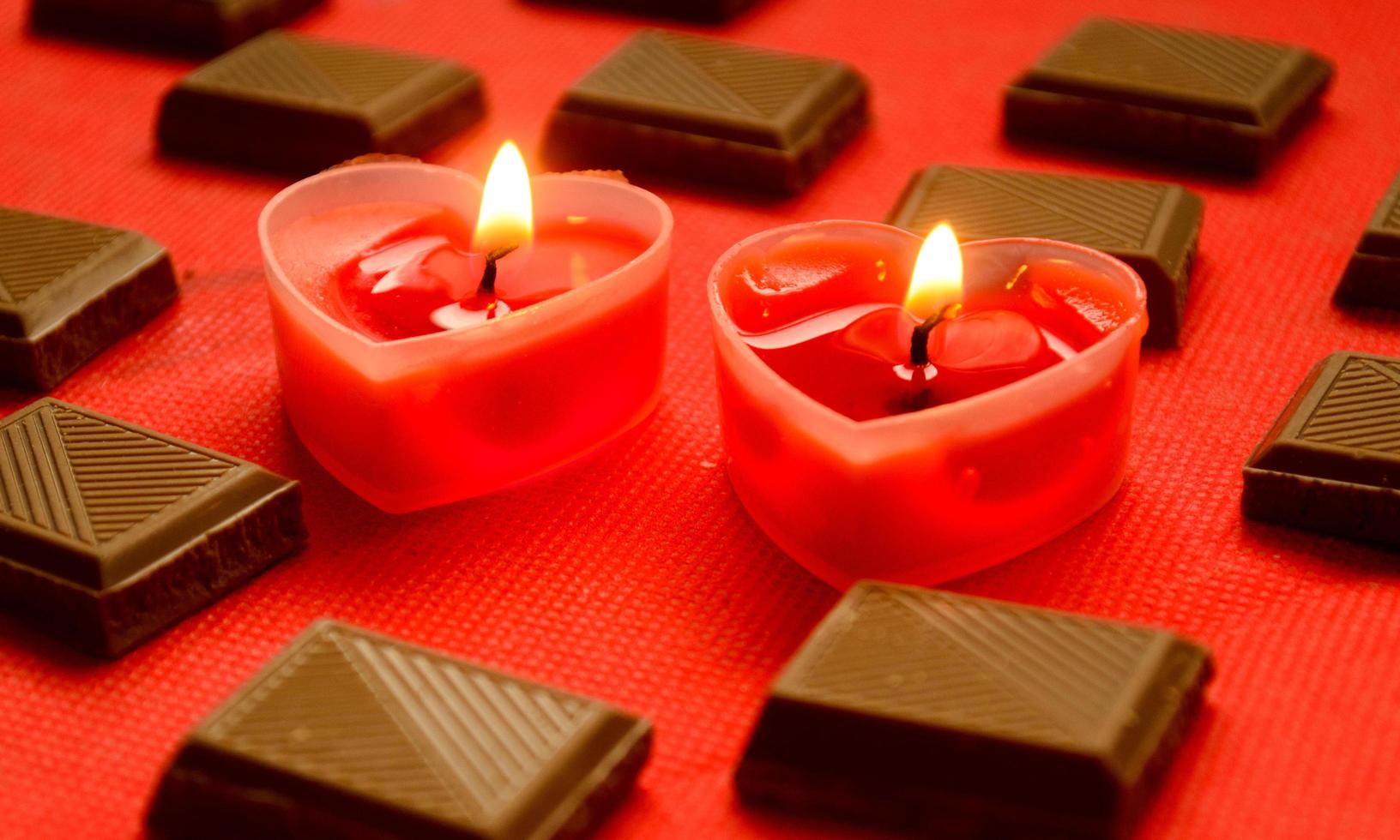 Two love burning hearts with chocolate bars on red background. photo