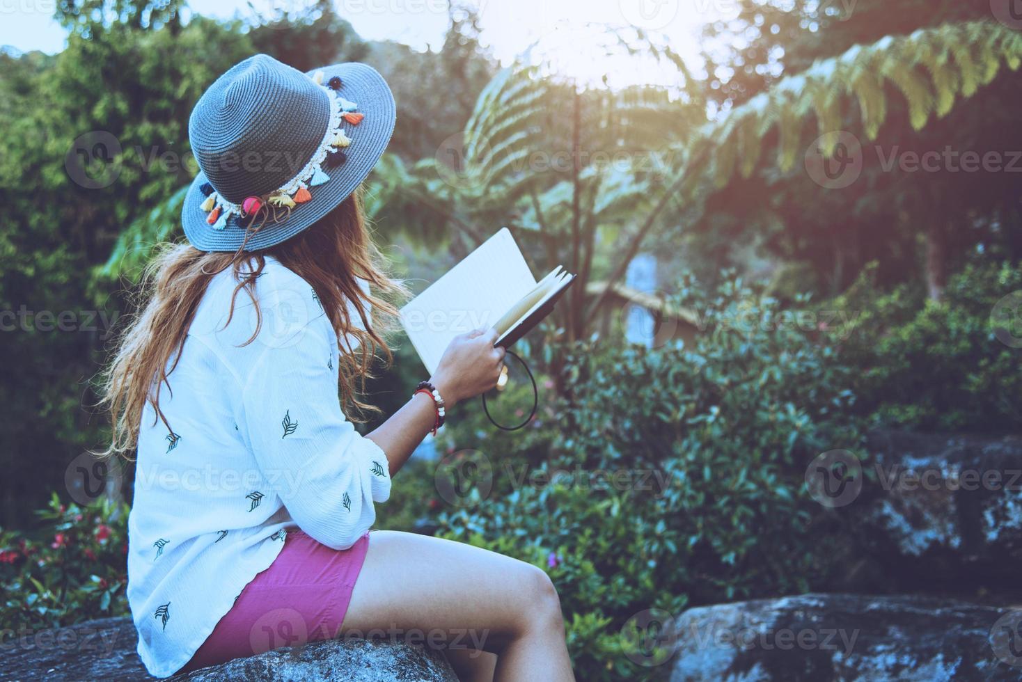 naturaleza de viaje de mujer asiática. viajar relajarse. estudiar leer un libro. educación sobre la naturaleza escribe una nota en un parque público en verano. En Tailandia foto