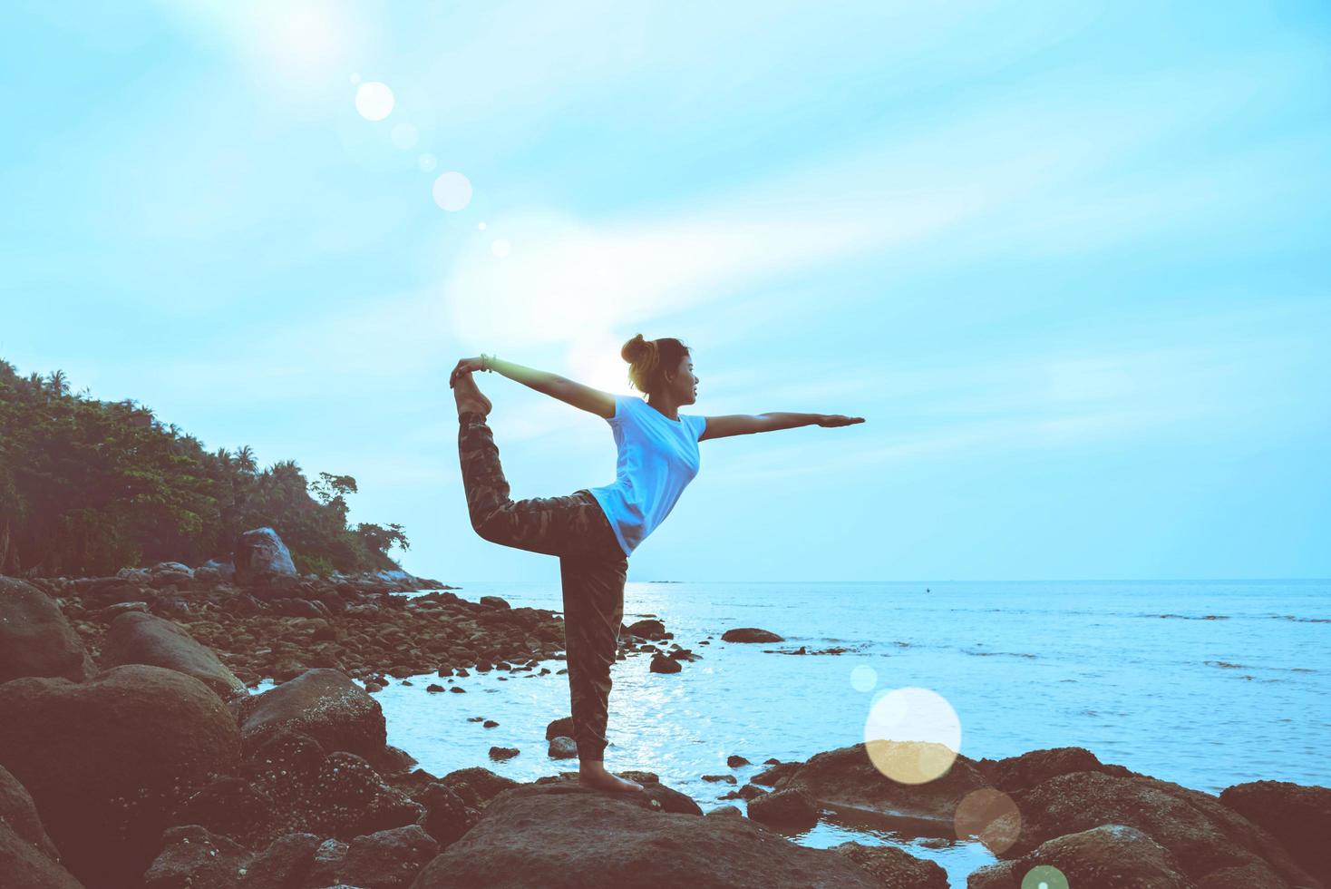 viaje de mujer asiática relajarse en las vacaciones. jugar si yoga. sobre las rocas junto al mar. foto