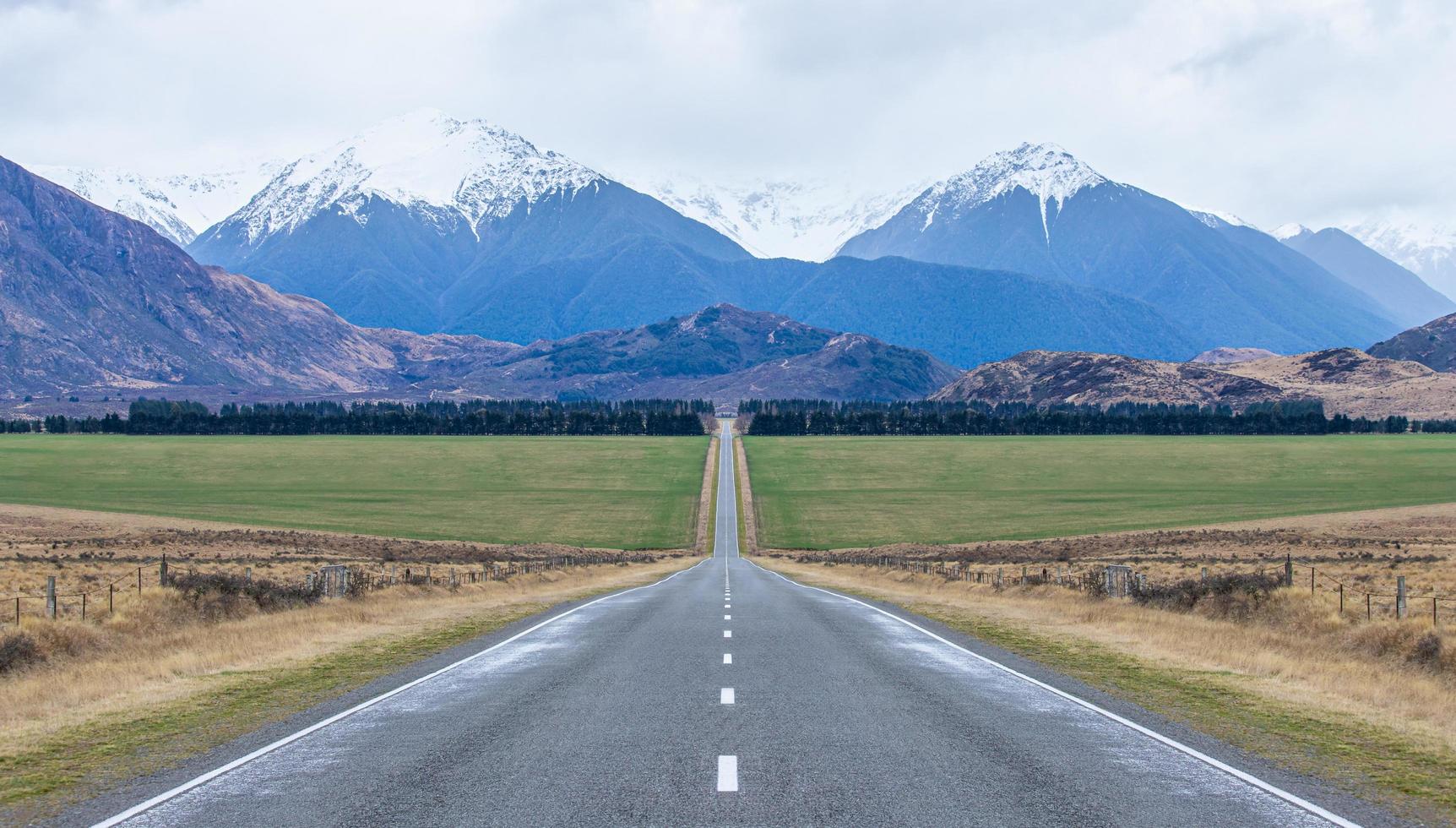 Panoramic view of long straight open icy road leading towards mountains in south island New Zealand photo