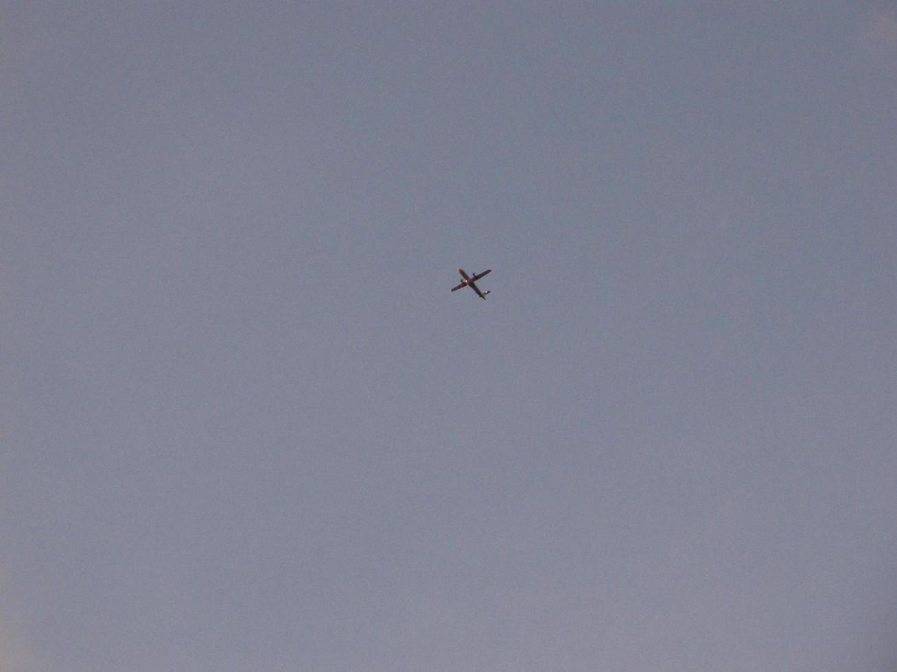 airplane with a slightly overcast blue sky background. this photo contains noise