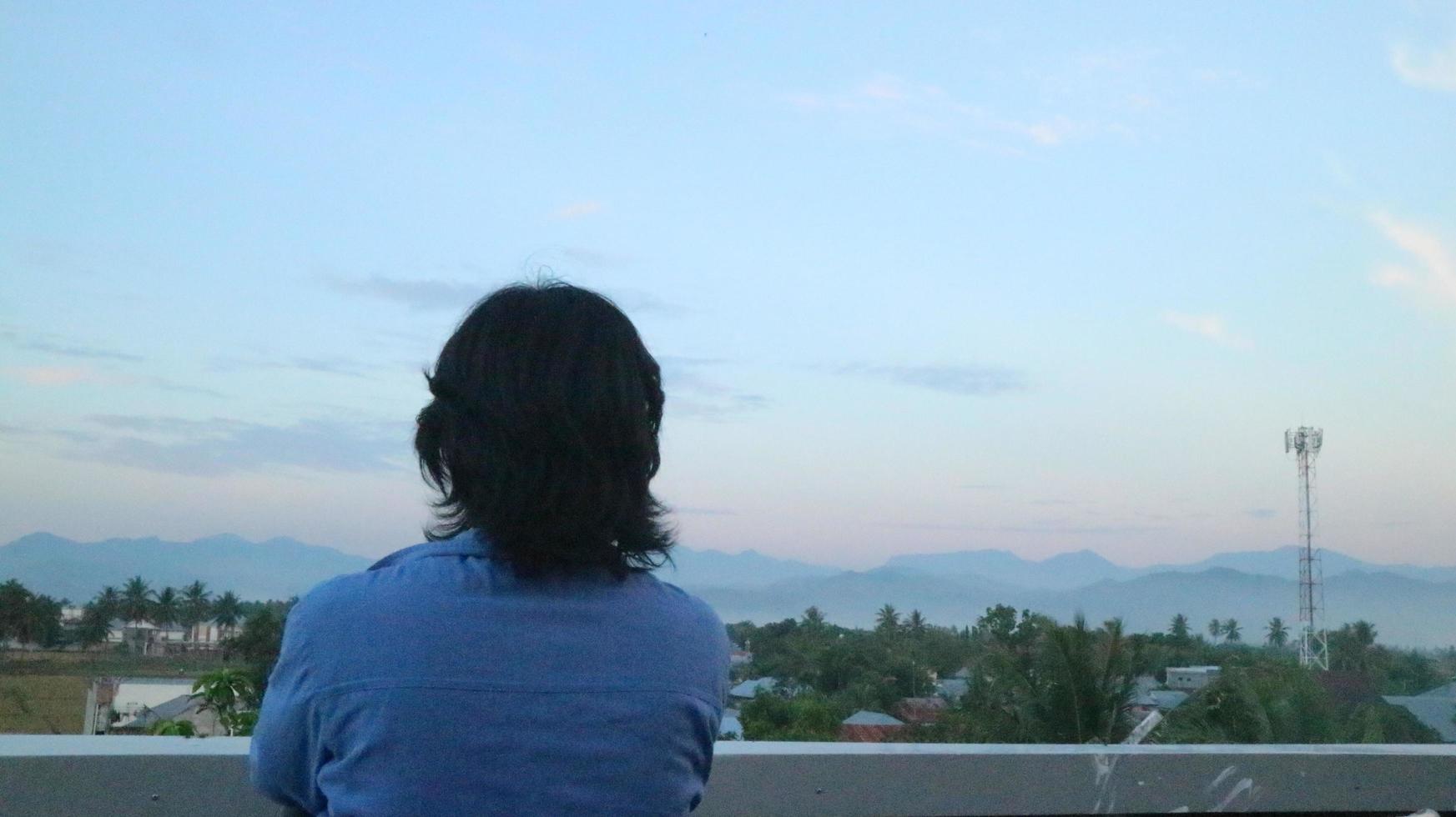 un hombre que está en la azotea de un edificio mientras disfruta de la belleza de la ciudad de gorontalo foto