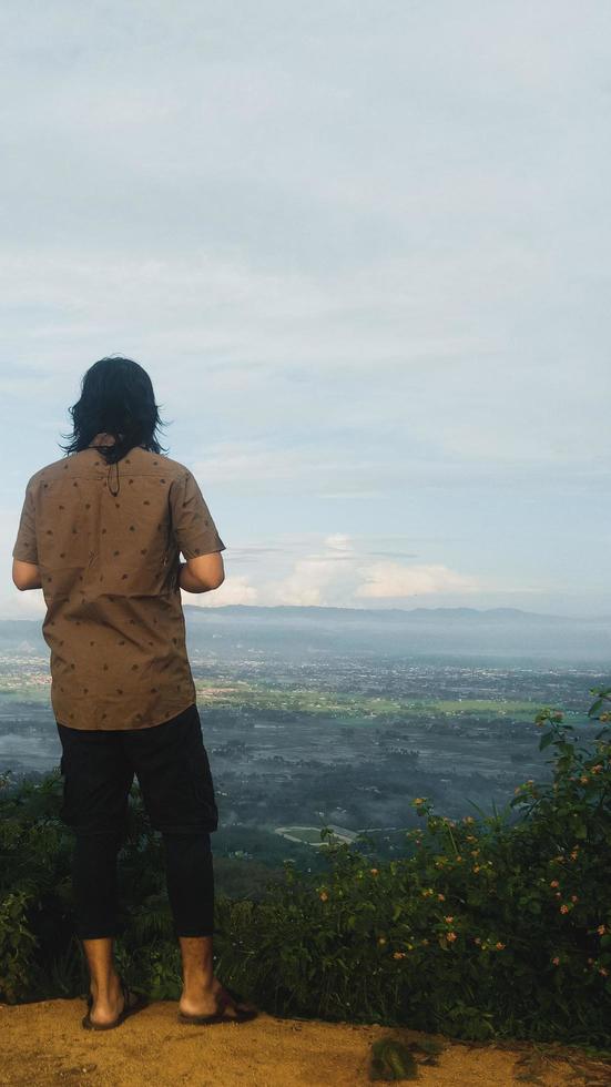 Back view of young man on mountain. The man looks back. Freedom traveler holiday concept photo