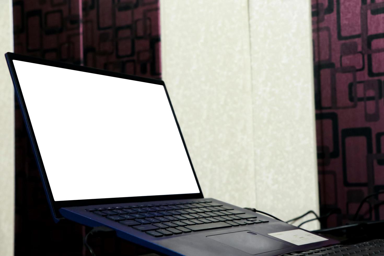 Laptop with blank white screen on the desk, mock up. Personal laptop computer on wood table in living room photo