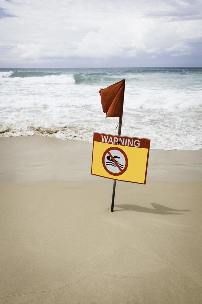 Señal de advertencia amarilla marina con una bandera roja. foto